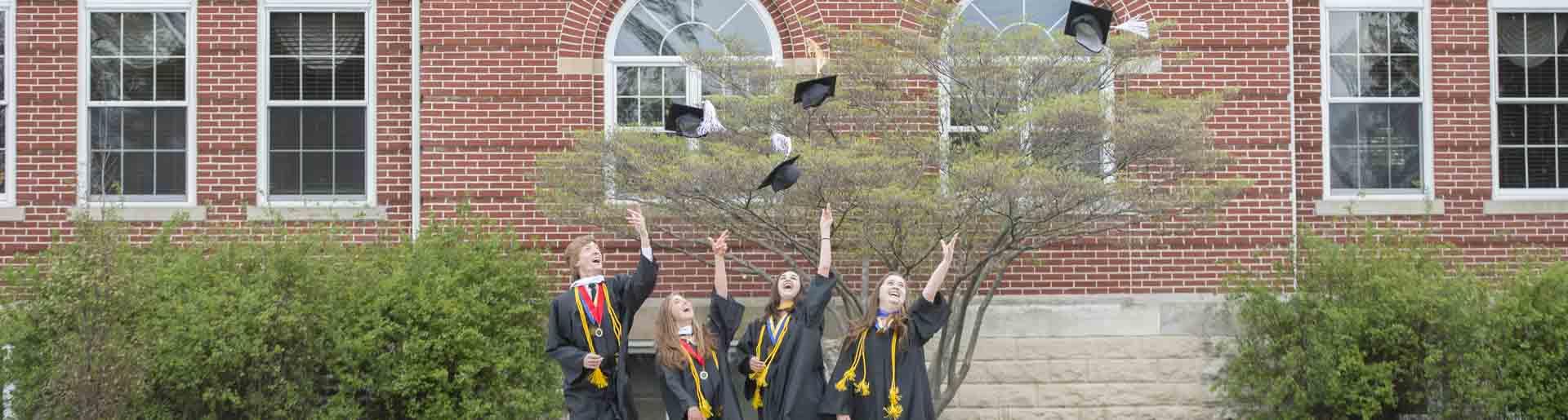 Oxford students throwing their caps while dressed in graduation regalia.